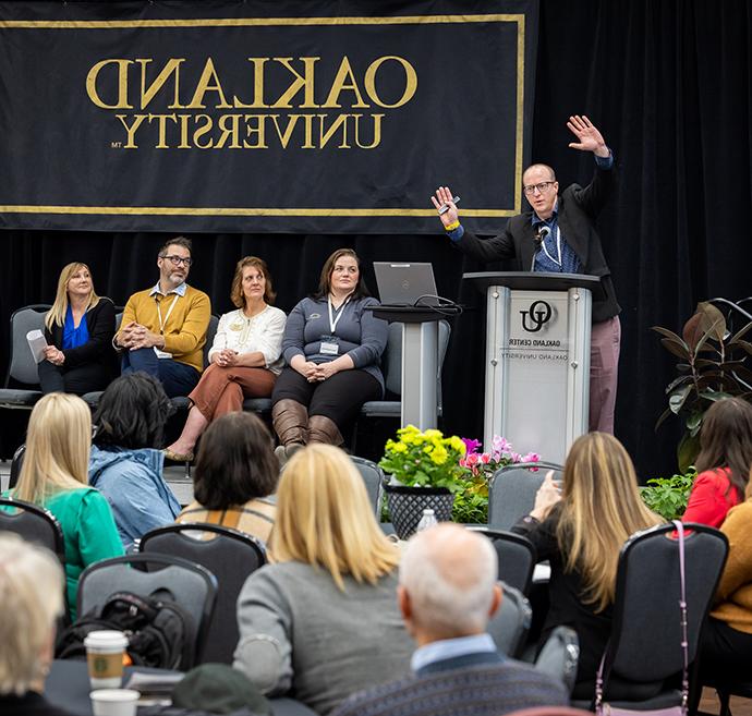 A person with their hands up at a podium giving a speech